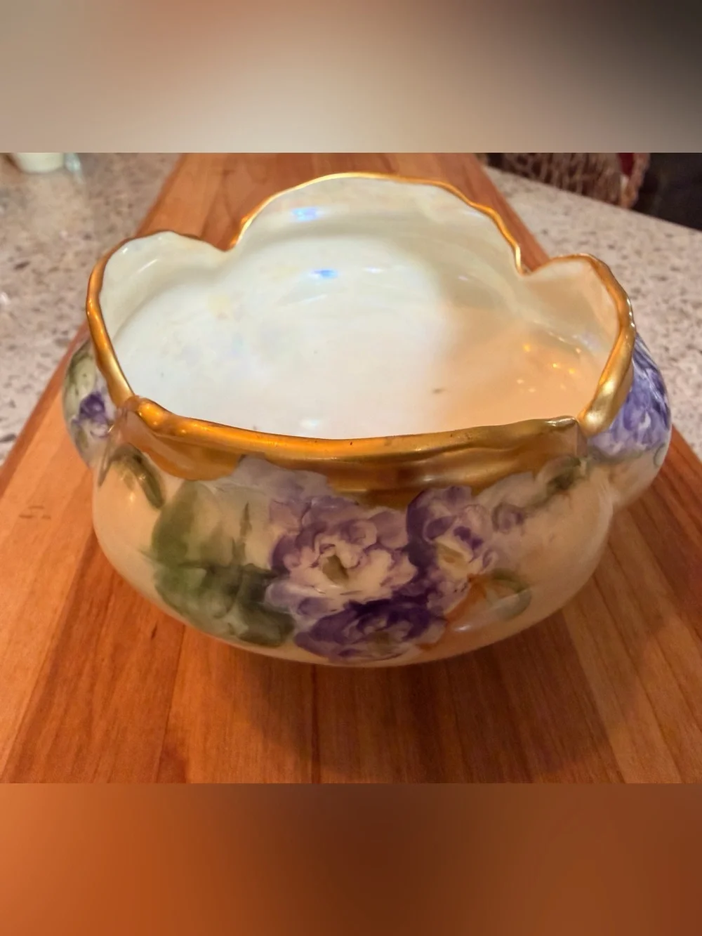 A hand-painted porcelain footed bowl with gilded rim and floral decoration.